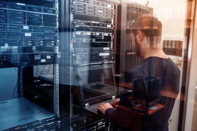 Man working at server rack with laptop.