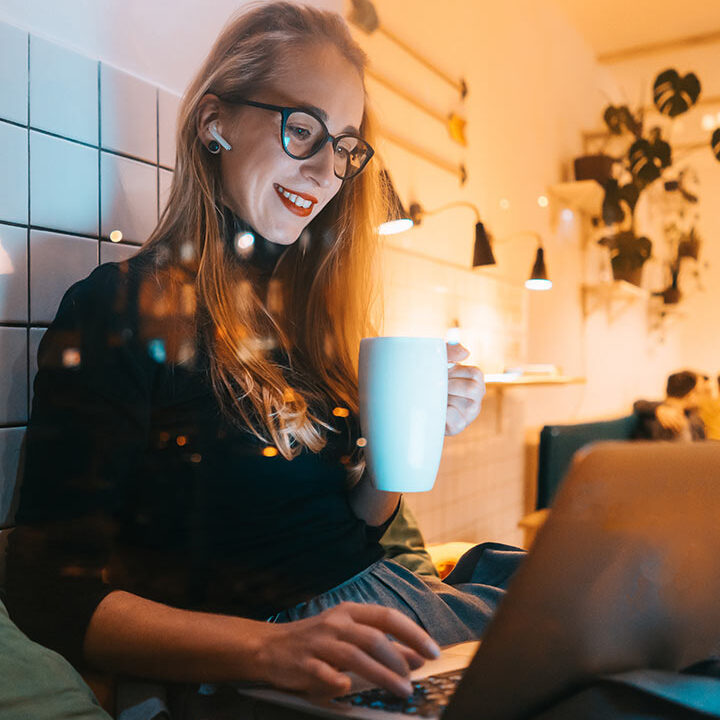 Woman working on laptop with coffee.