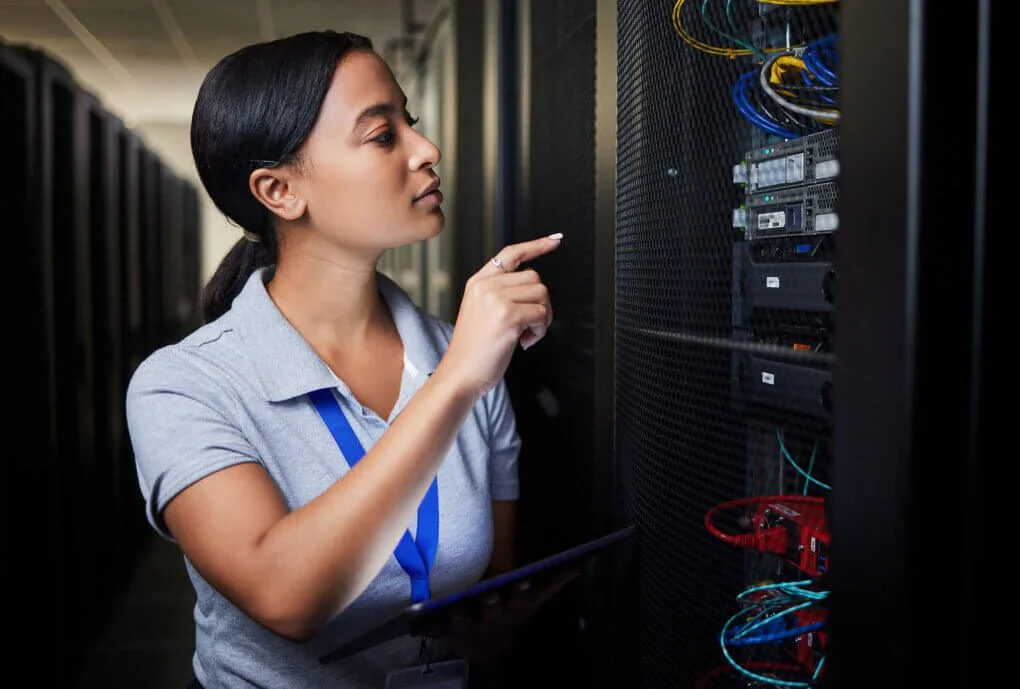 Woman inspecting server rack in data center.