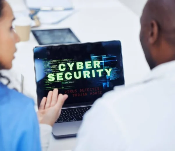 Two people discussing cyber security on laptop.