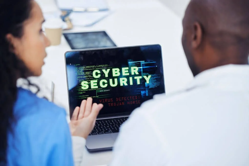 Two people discussing cyber security on laptop.