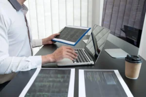 Person working on laptop and documents.