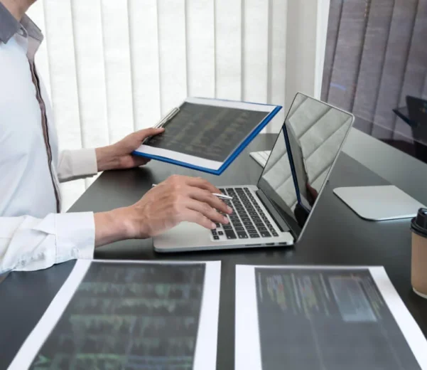 Person working on laptop and documents.