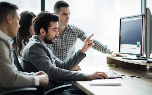 Man pointing at computer screen in meeting.