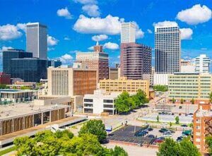 Oklahoma City skyline with skyscrapers and green trees.